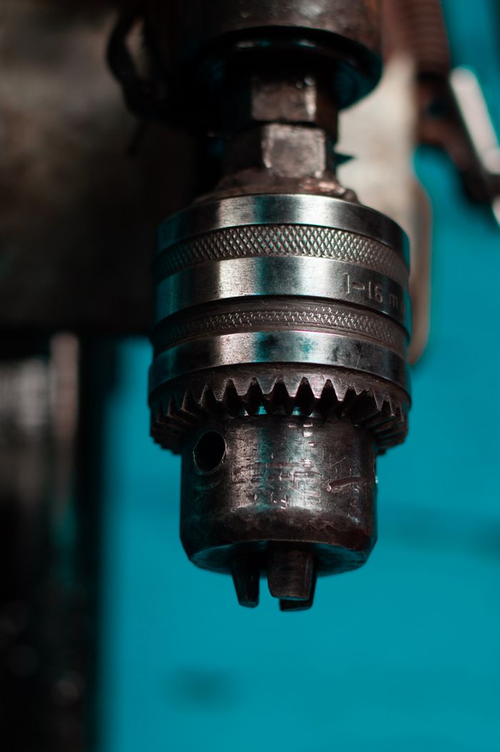 Industrial drill chuck in focus with blue background showcasing metal details.
